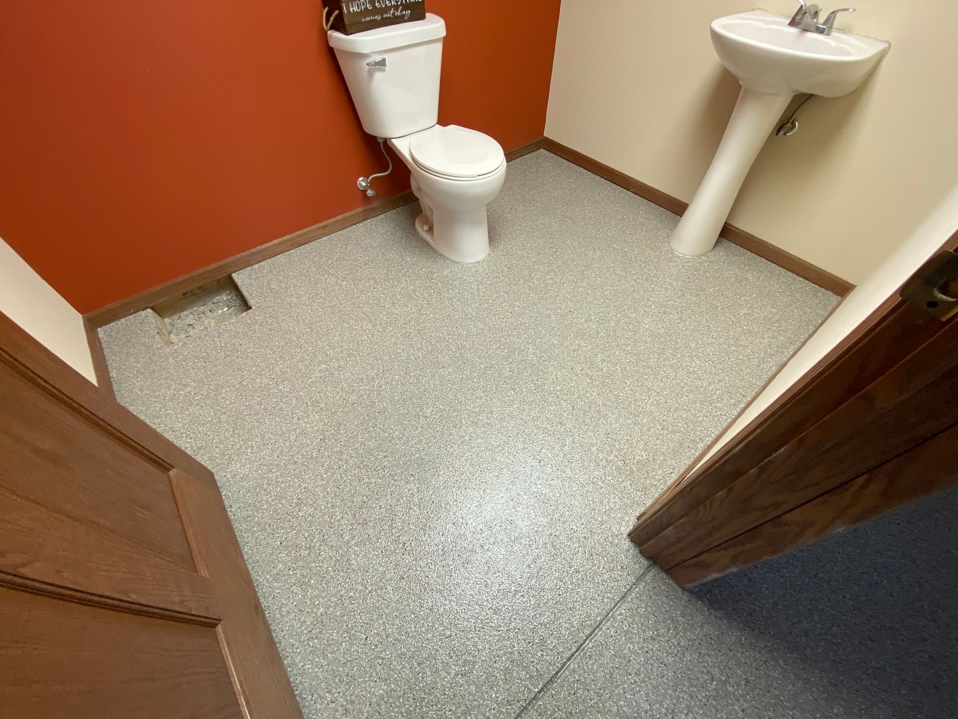 Small bathroom with toilet, pedestal sink, and speckled gray floor, viewed from the doorway