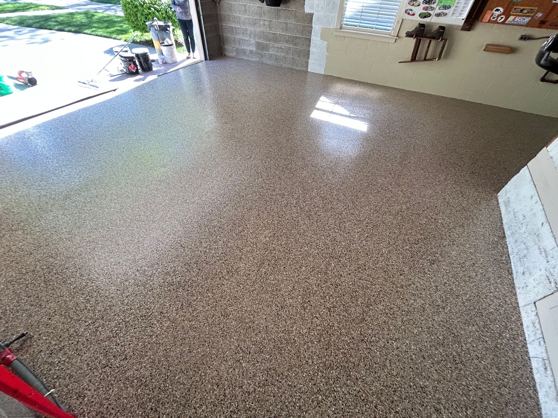 Empty speckled floor beside an open garage with bright daylight outside