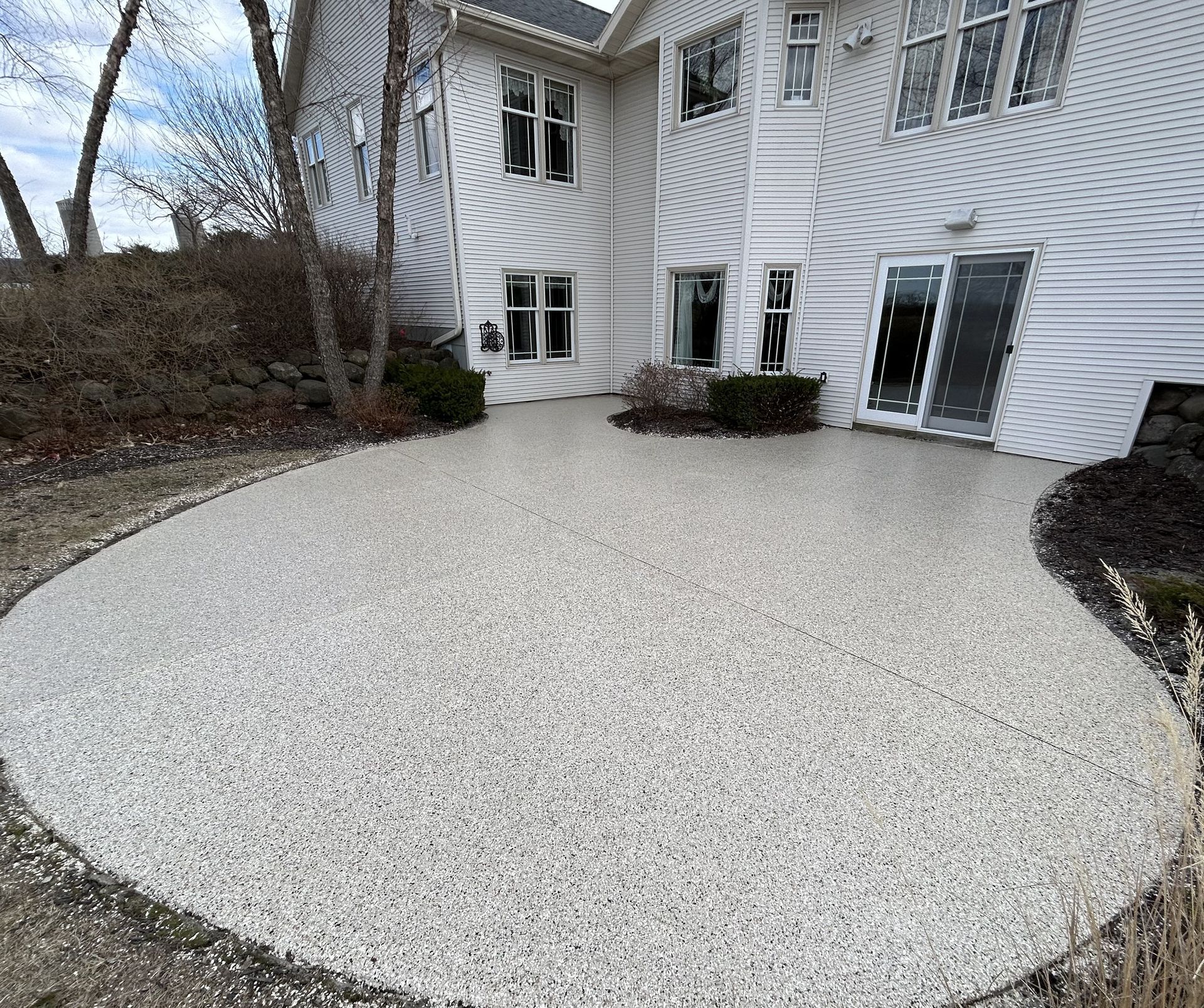 White stone patio beside a house with white siding and sliding glass doors