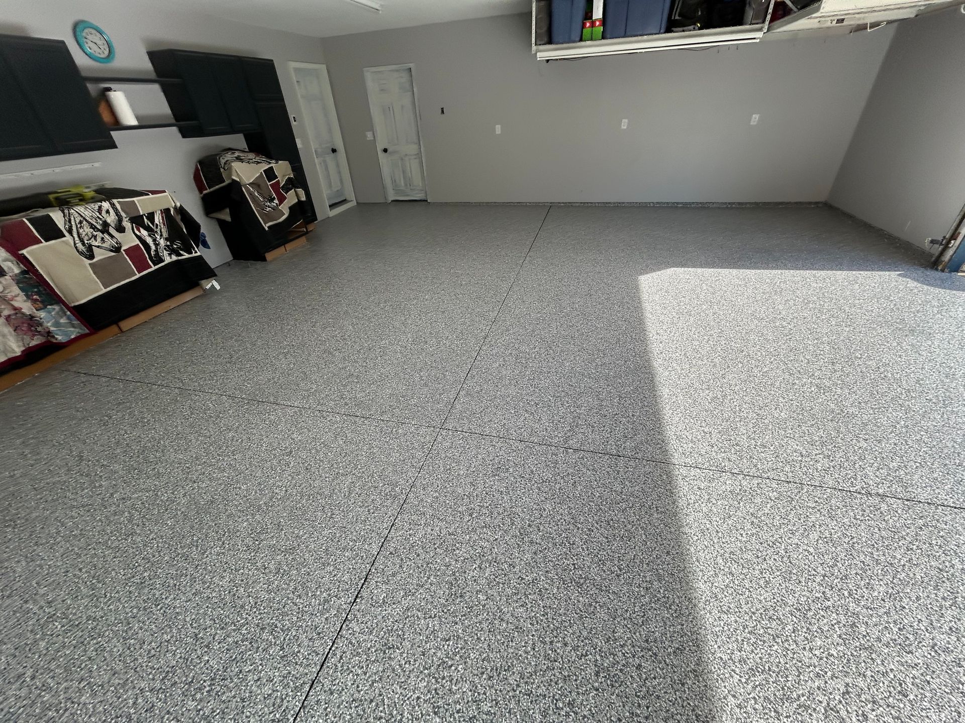Empty gray-carpeted room with shelves along the walls and sunlight on the floor.