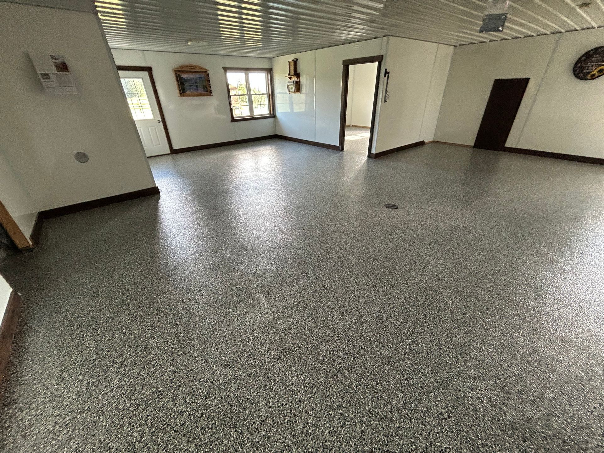Empty speckled-floored room with white walls, windows, and an open doorway