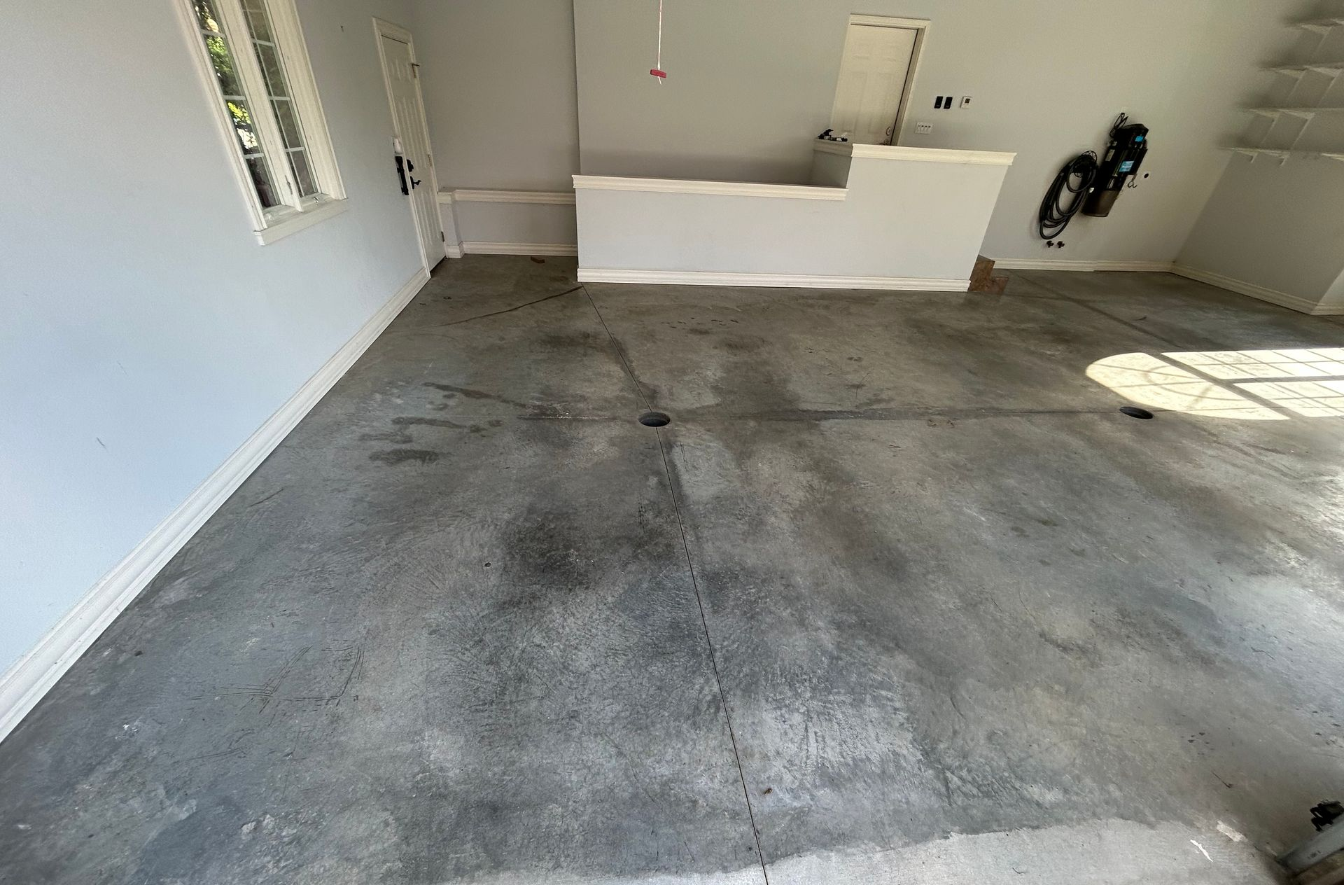 Empty concrete garage with white walls and a small workbench in the back corner.