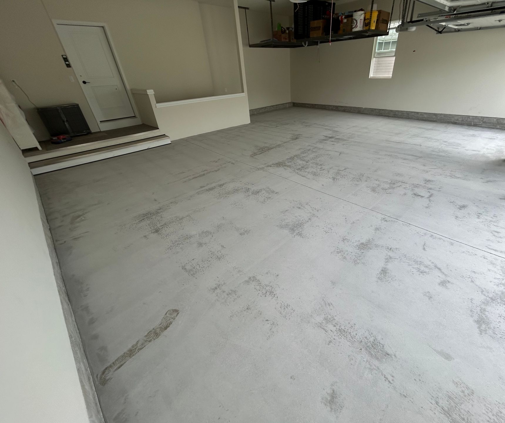 Empty garage with a freshly coated light gray floor and open storage area.