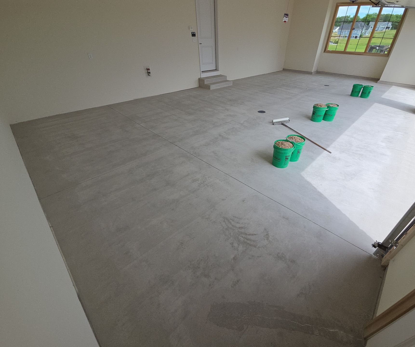 Partially tiled room with green buckets and a window at the far end
