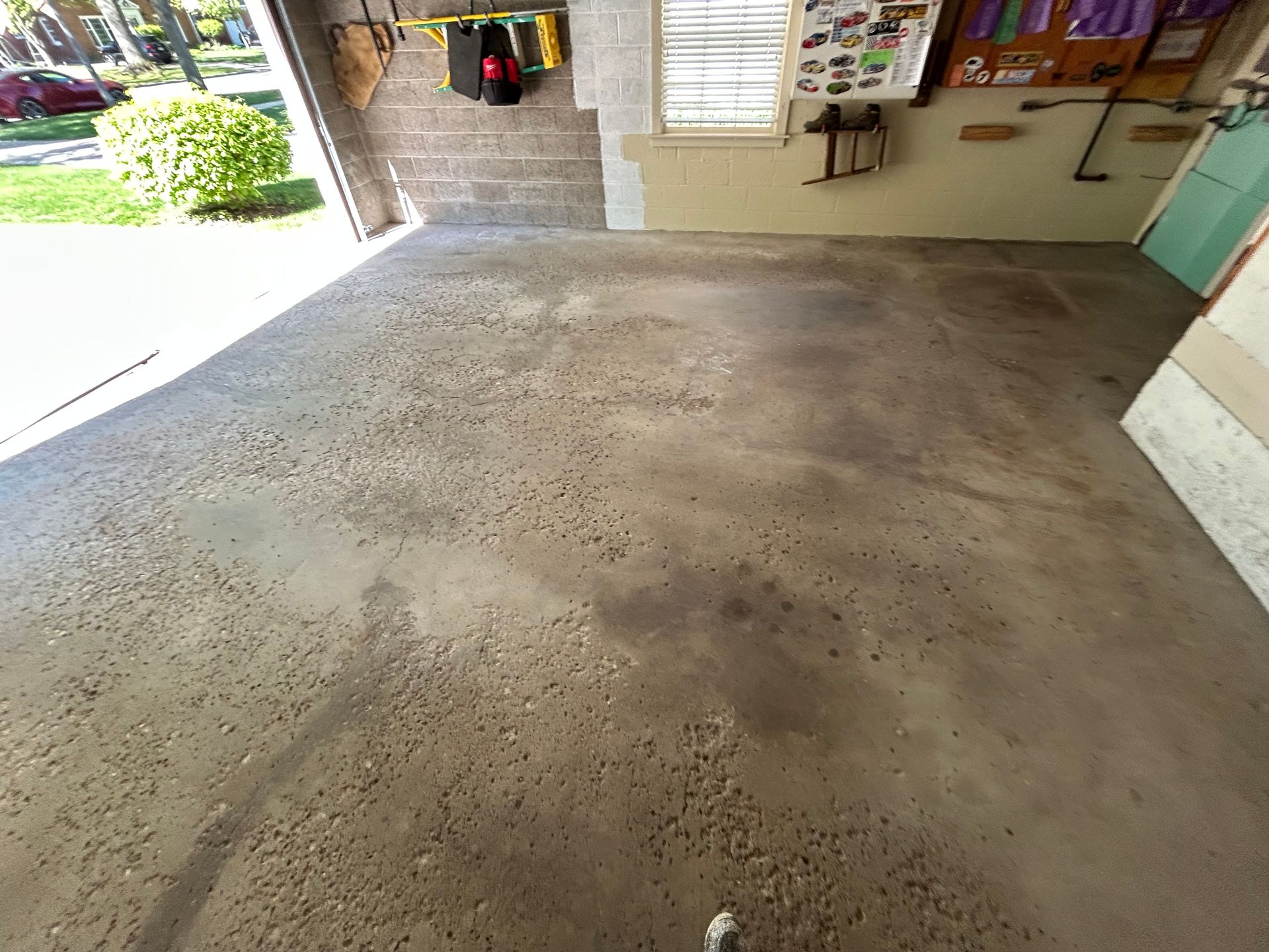 Empty concrete floor inside a garage or workshop, with an open doorway and shelving on the right.