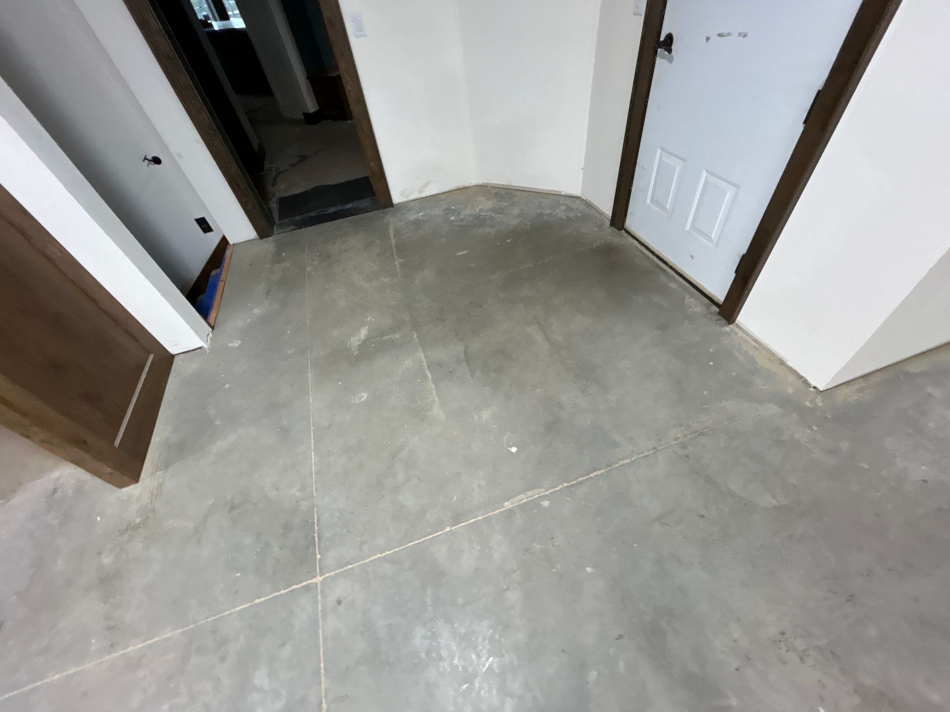Empty hallway with gray tiled floor, white walls, and open doorways on both sides