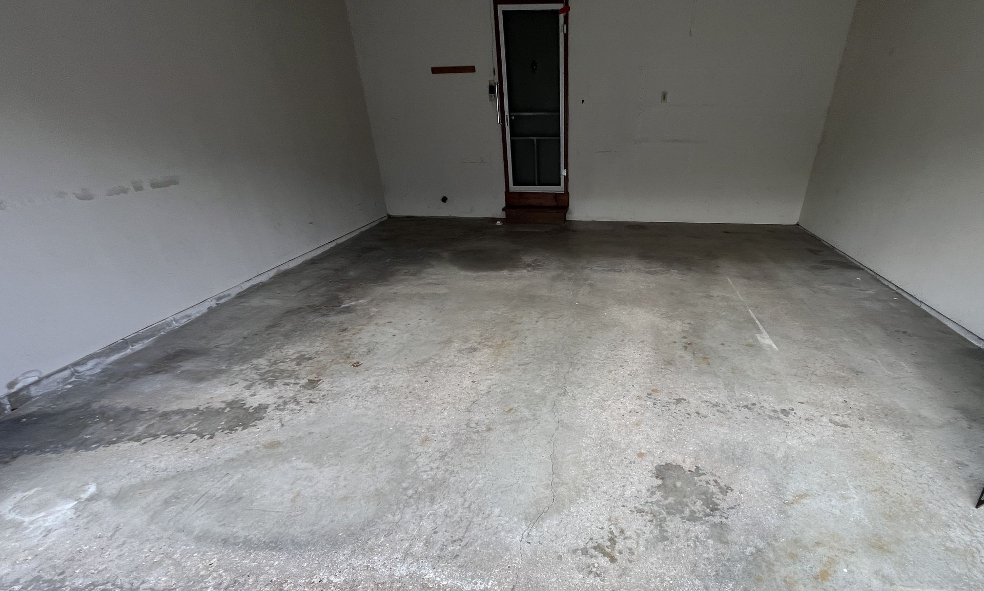 Empty concrete garage with a small door at the back wall