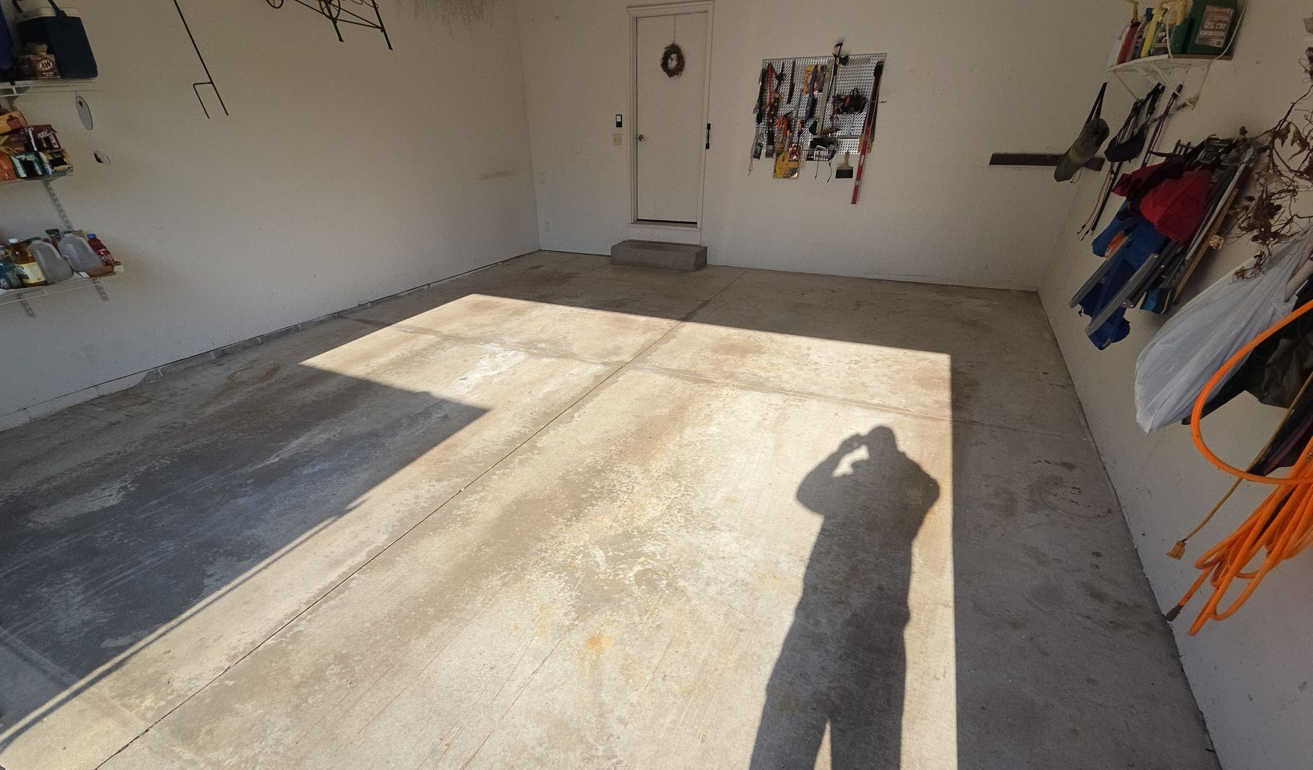 Empty garage with freshly poured concrete slab and a person’s shadow on the floor