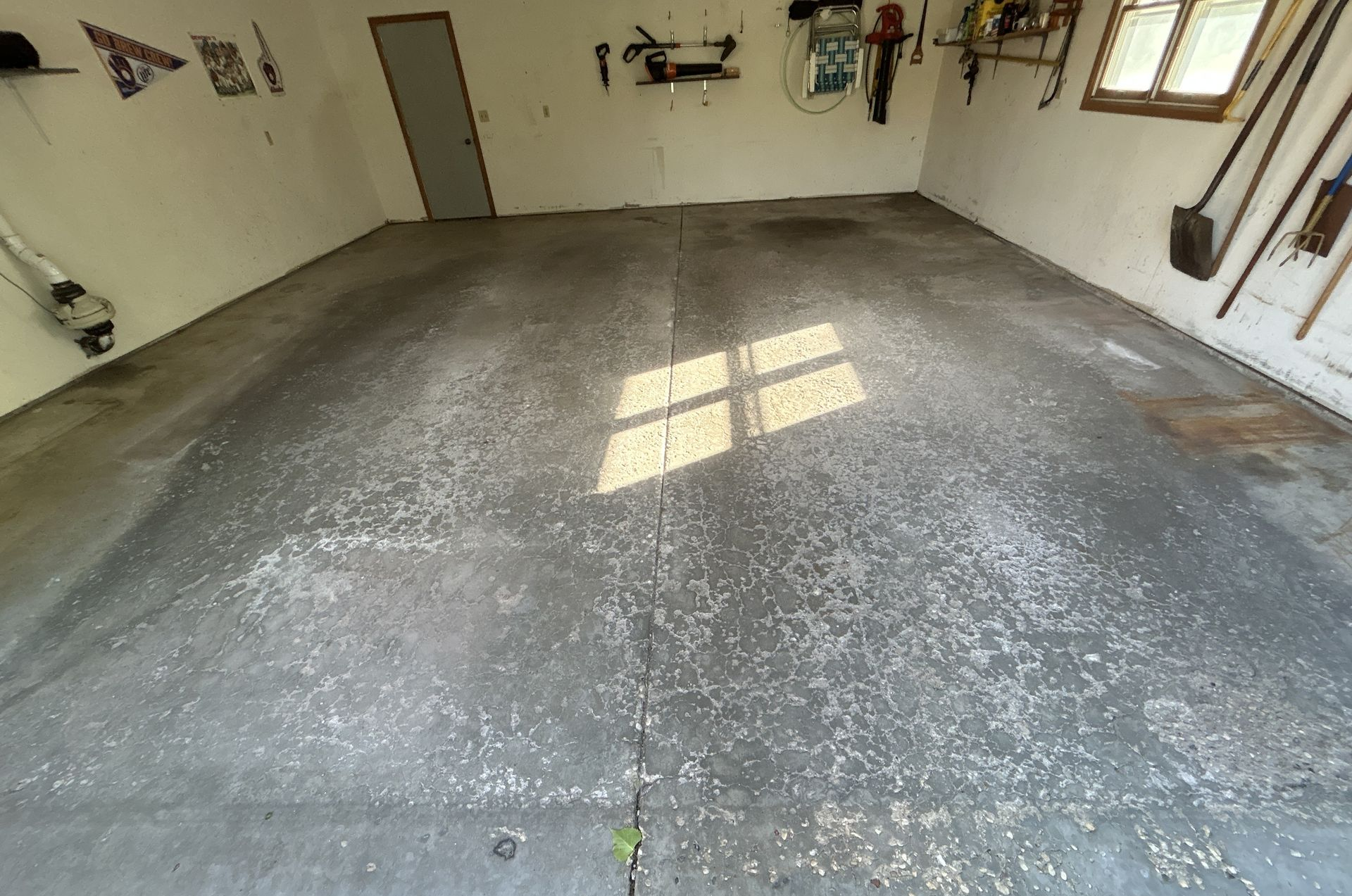 Empty garage with gray concrete floor and sunlight coming through a window.