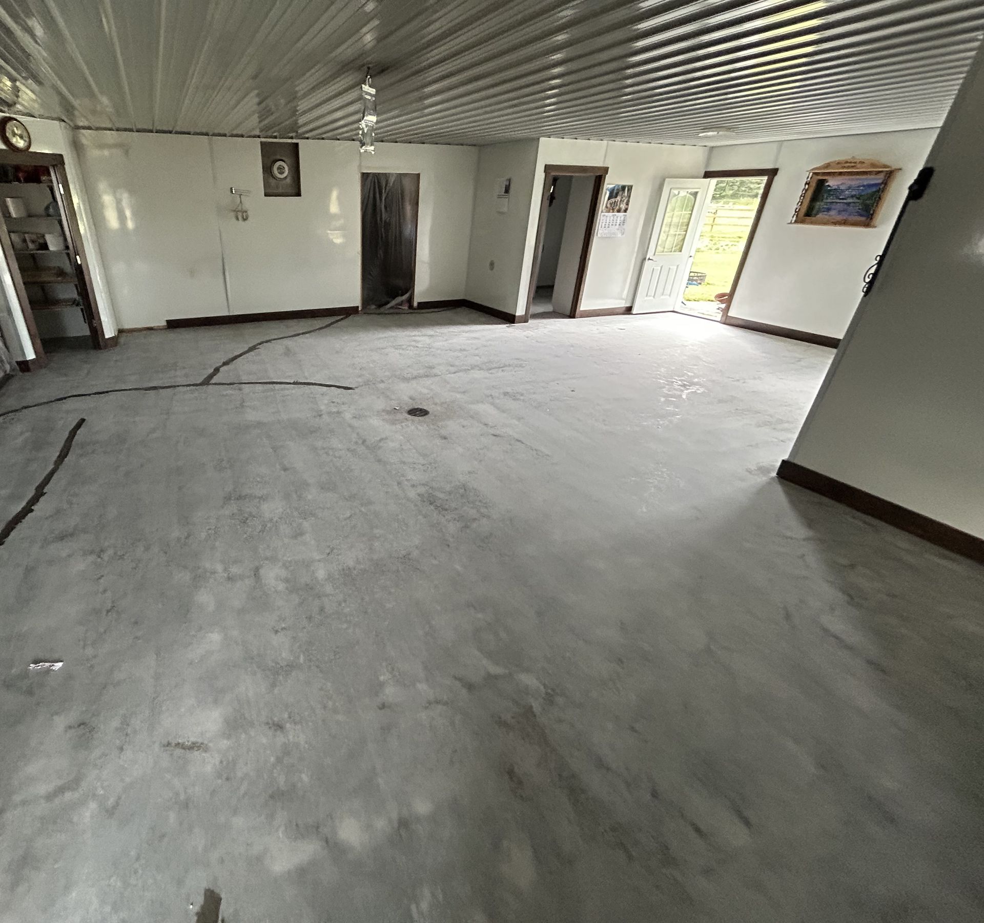 Empty unfurnished room with white walls, patterned ceiling, and open doorway to a bright outdoor view.