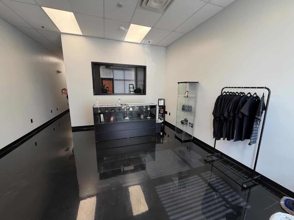 Empty modern lobby with black tile floor, reception desk, and coat rack with jackets