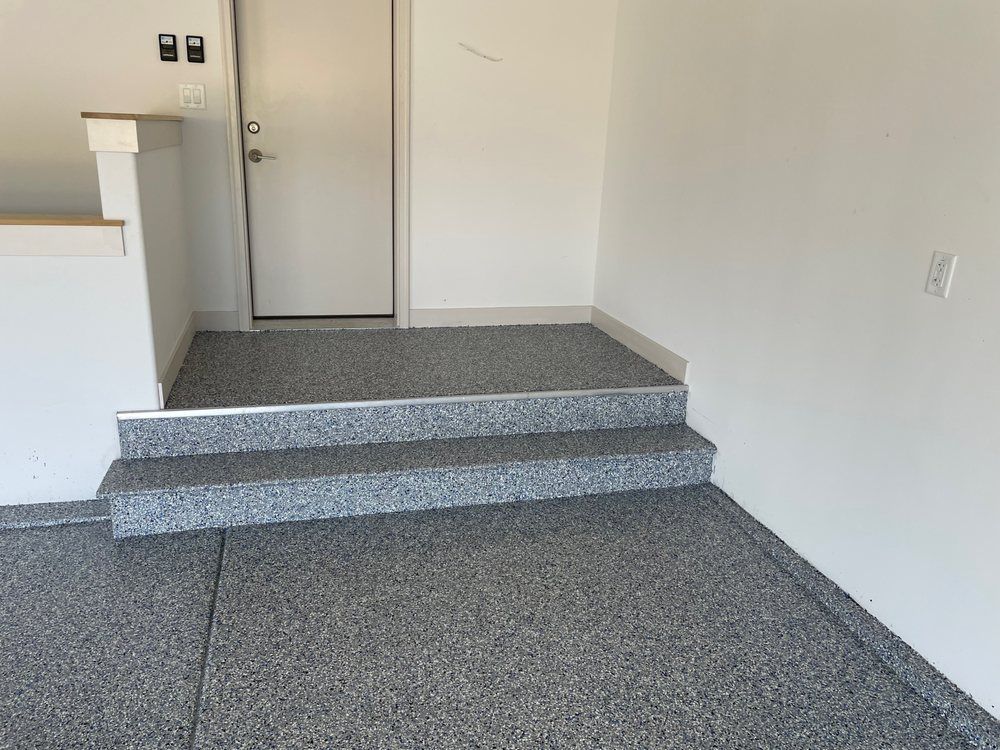 Carpeted entryway with two steps leading to a white door and plain white walls