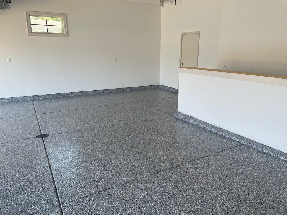 Empty room with gray speckled floor, white walls, small window, and a half wall counter.