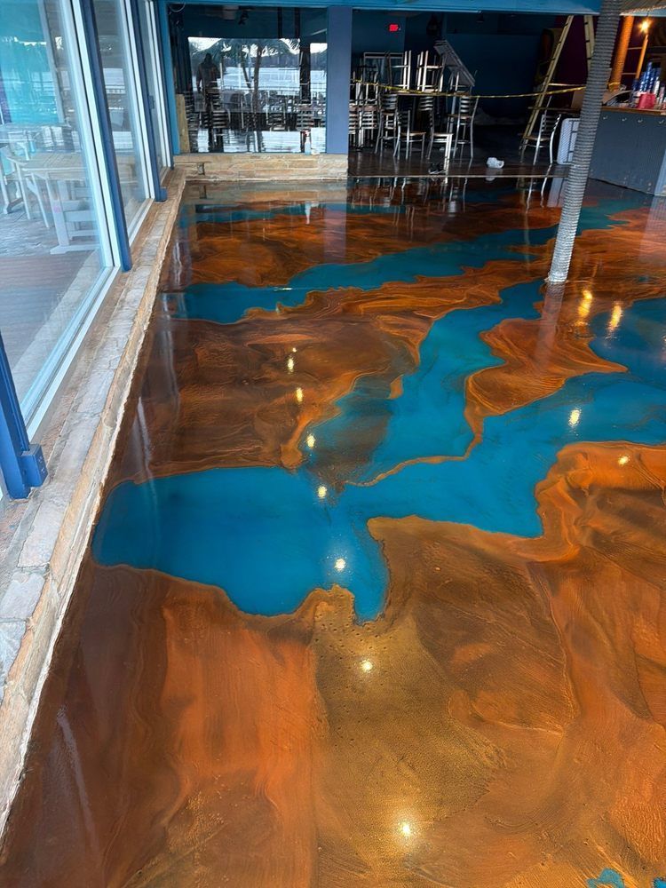 Glossy blue and brown epoxy floor in a modern indoor space with glass walls and reflections