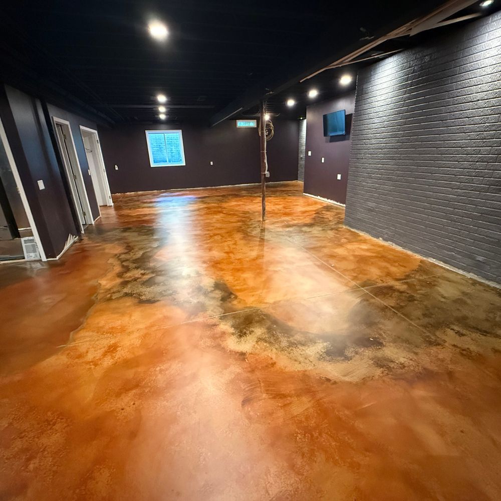 Empty room with glossy orange concrete floor, dark walls, and ceiling lights reflected throughout.