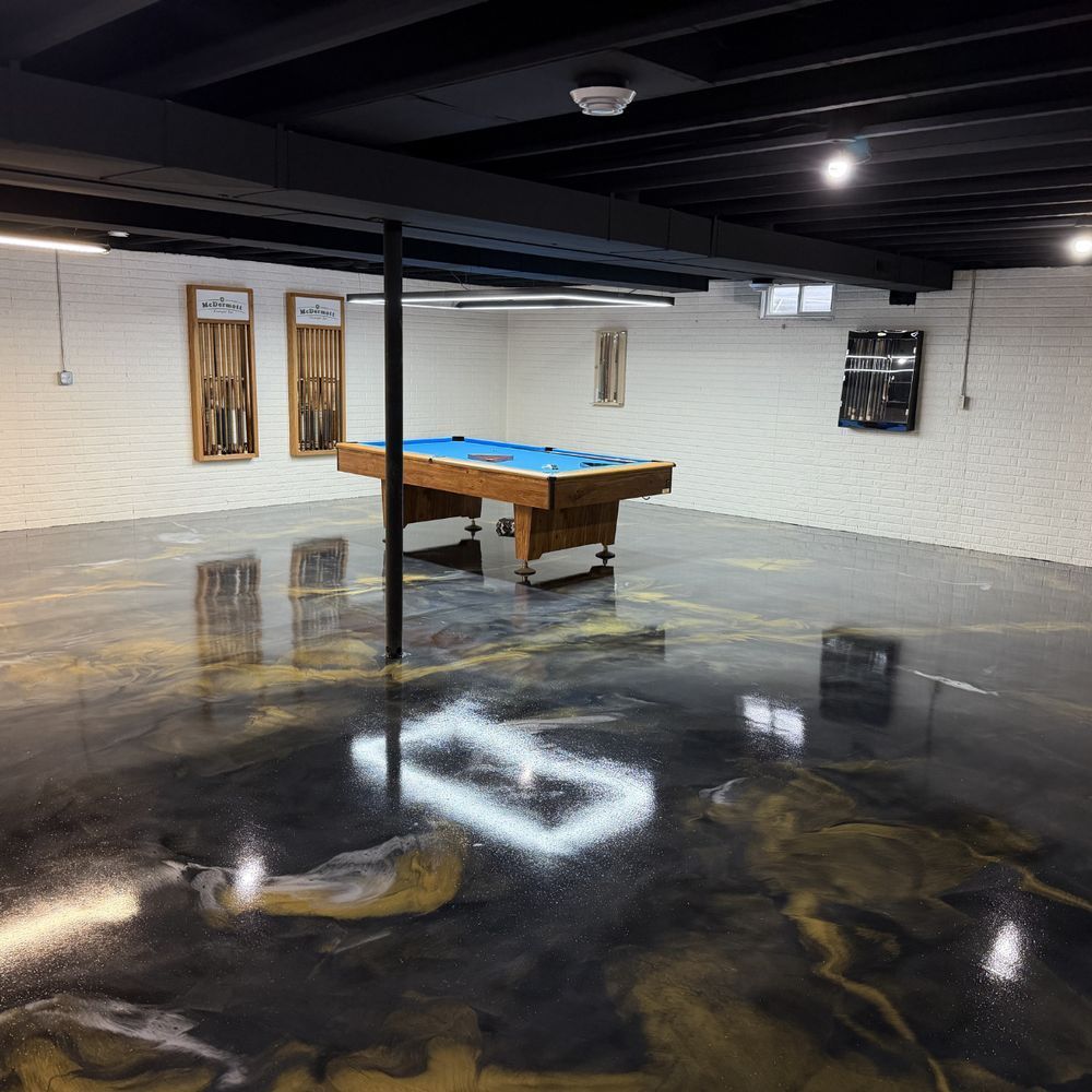 Basement game room with a pool table and glossy black floor reflecting lights.