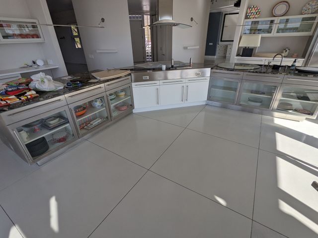 Bright kitchen with white cabinets, glass display case, and tiled floor, seen from a low angle.