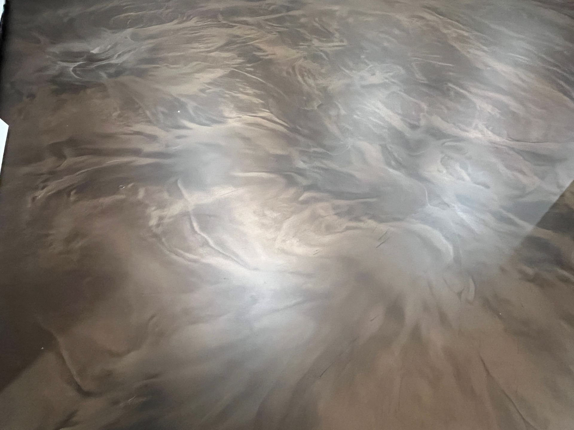 Close-up of a gray-brown, marbled textured surface with a bright light reflection