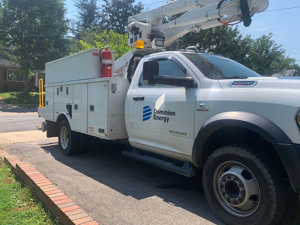 White Oak Ridge Energy utility truck parked on a driveway, with an extended arm and storage compartments.