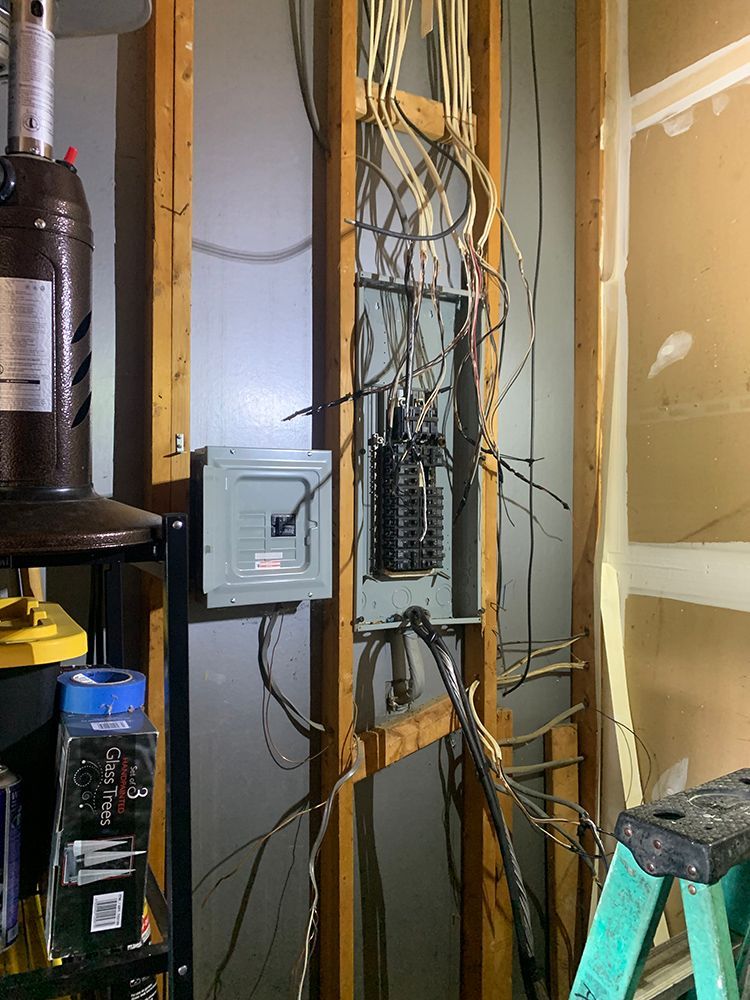 Electrical panel with exposed wiring on wooden frame. Wires hanging down.