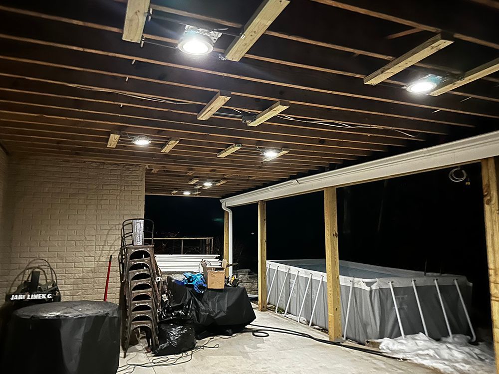 Outdoor covered area with lights, a pool, chairs, and covered items.