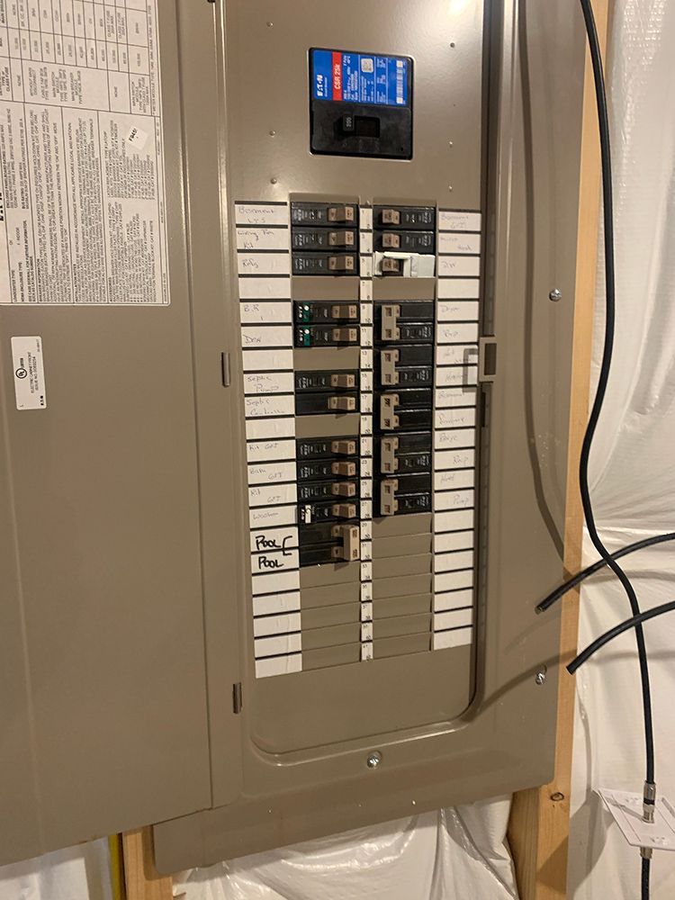 Electric panel with multiple circuit breakers in a residential setting.