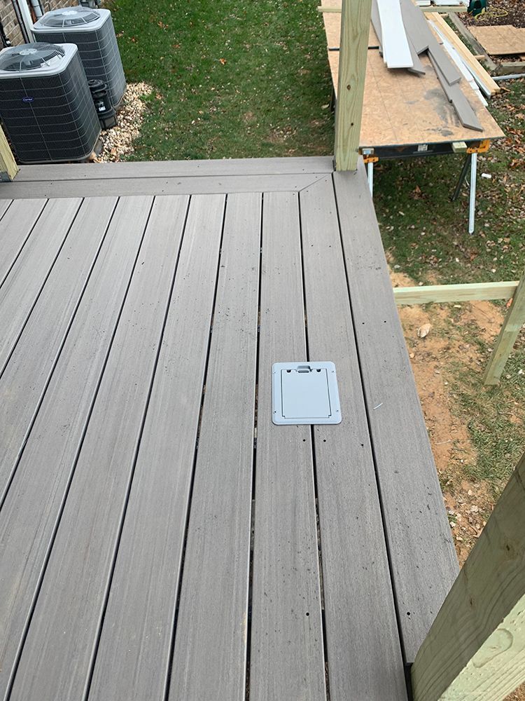 Gray deck with built-in electrical outlet. Air conditioning units are in the background.