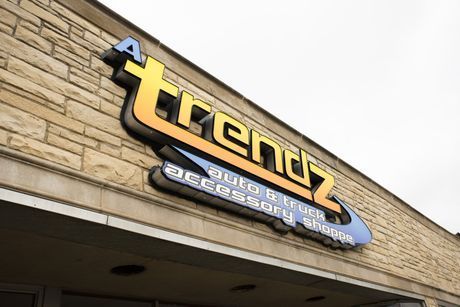 Trenz sign on a stone storefront, with yellow and black lettering and a blue oval logo.