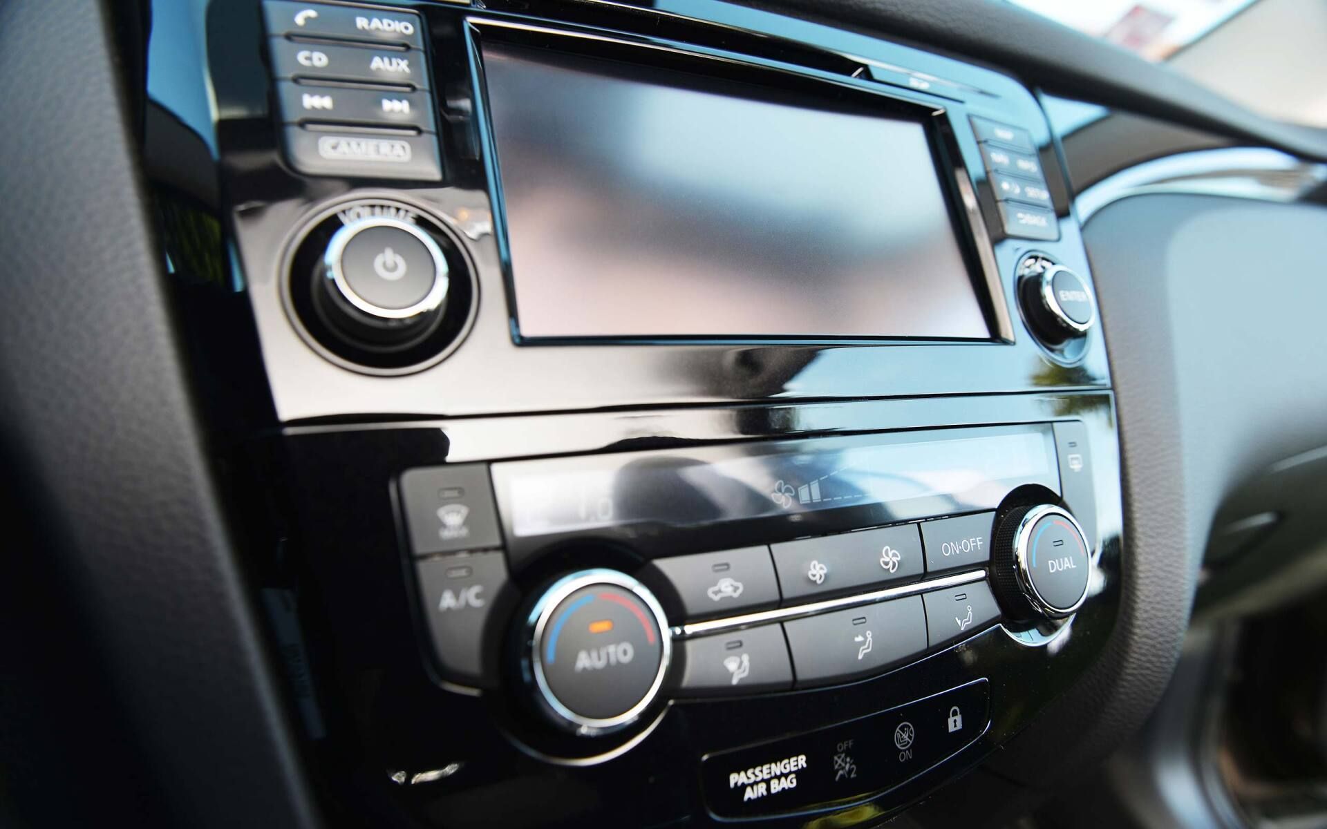Car dashboard center console with touchscreen, climate controls, and radio buttons in black and silver.