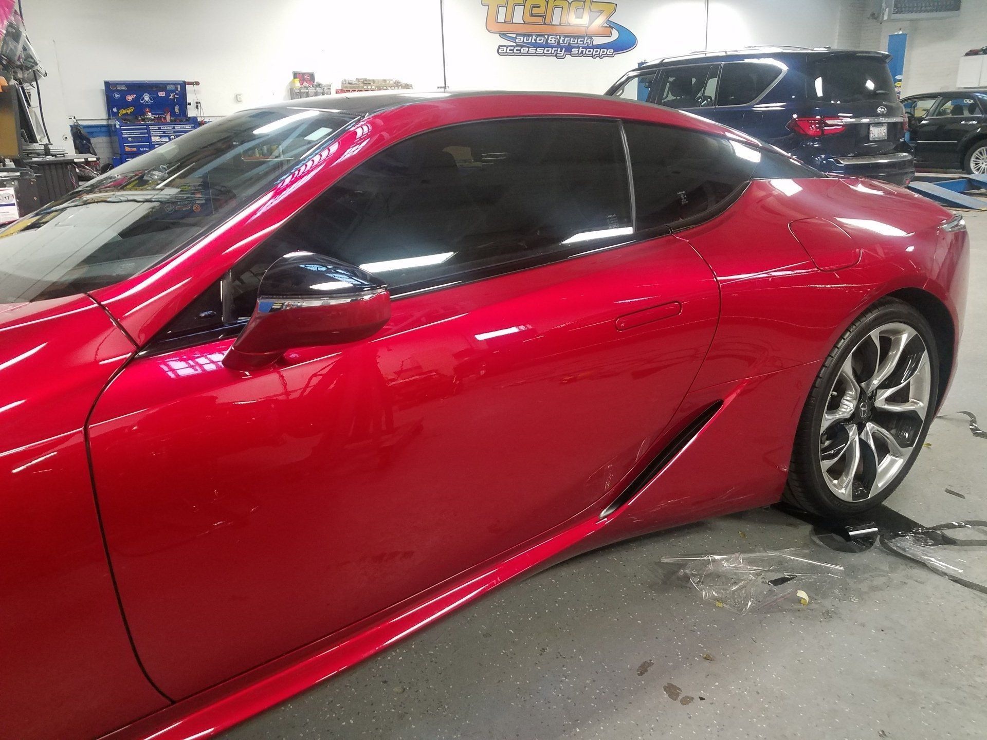 Red sports car in a garage, side view with glossy paint and dark tinted windows