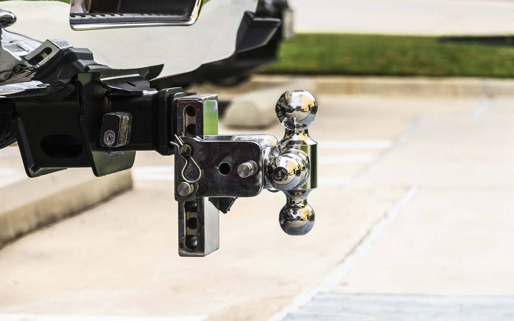 Trailer hitch with shiny chrome tow ball mounted on a black vehicle hitch receiver outdoors