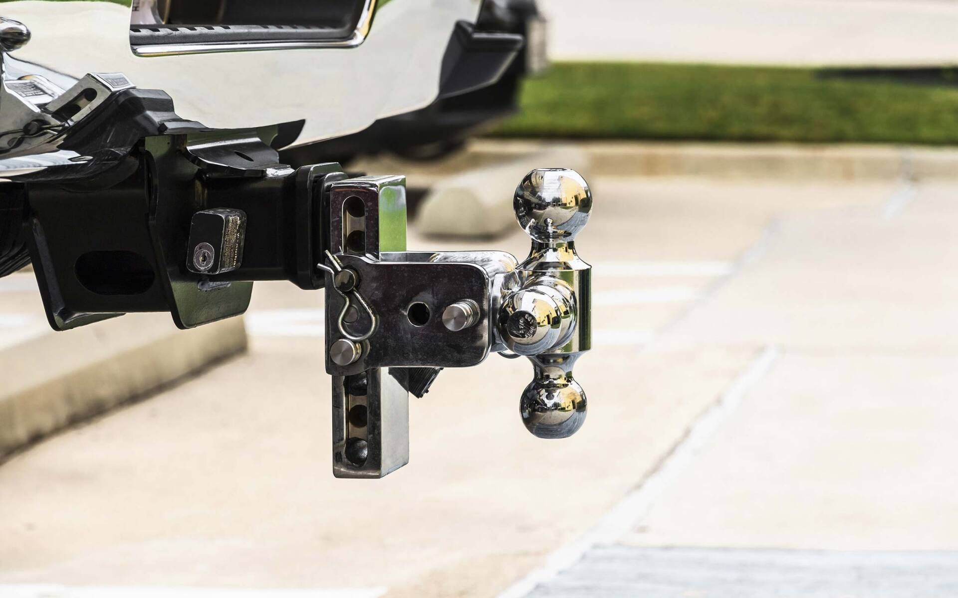 Trailer hitch with shiny chrome tow ball mounted on a black vehicle hitch receiver outdoors
