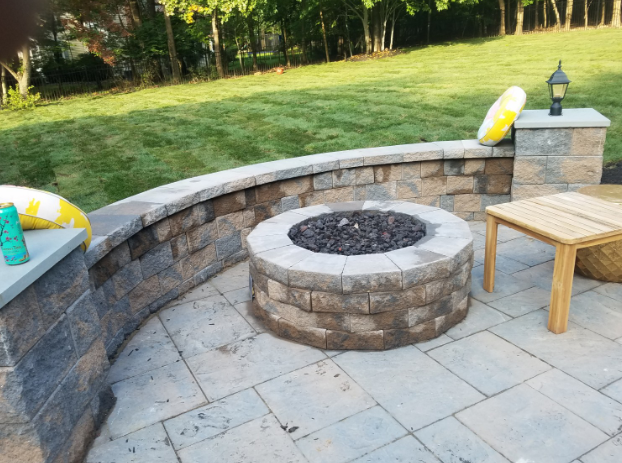 Stone fire pit and retaining wall on patio; yellow floatie and small table nearby.