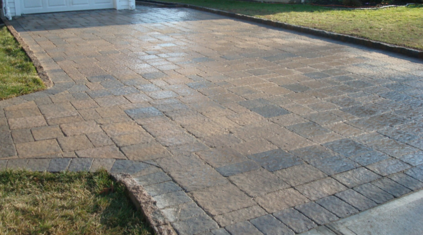 Brick paved driveway with grass edges leading to a garage.