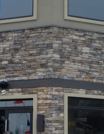 Stone exterior building corner with windows and dark trim.