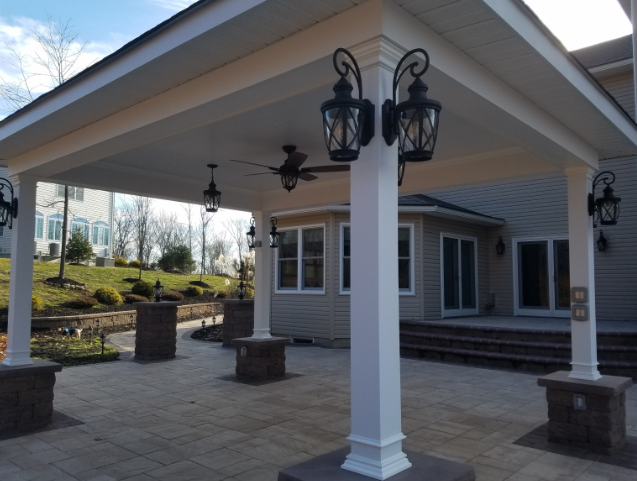 Covered patio with white columns, outdoor lighting, and stone flooring.
