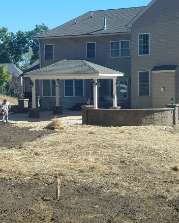 Backyard patio with a gazebo, fire pit, and a house. Construction is in progress.