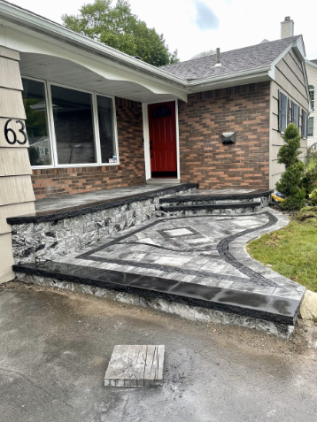 Brick and stone walkway and steps leading to a house with a red door.