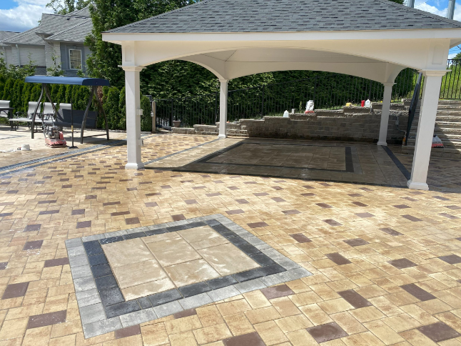 Outdoor patio with gazebo, brick pavers in various colors, steps leading uphill.