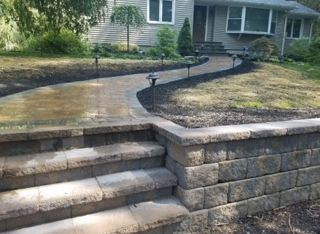 Stone steps and walkway leading to a house with landscaping and solar lights.