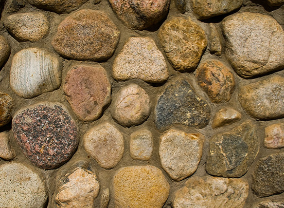 Close-up of a wall made of rounded, colorful stones set in tan mortar.
