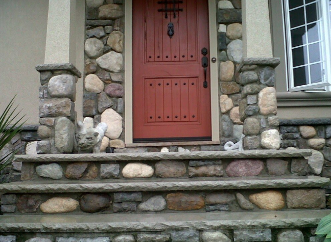 Stone facade entrance with steps, columns, and a red door.