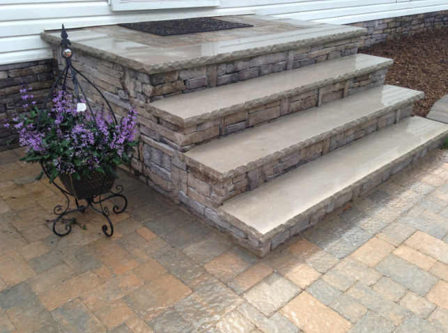 Stone steps leading up to a house with a flower pot on the side.