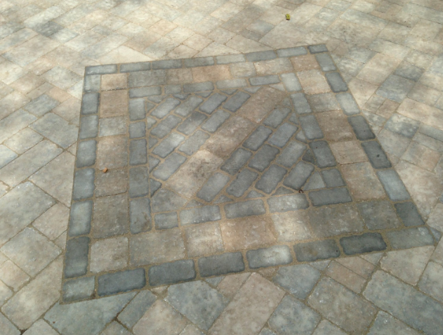 Square brick patio with patterned center and border, various neutral tones.