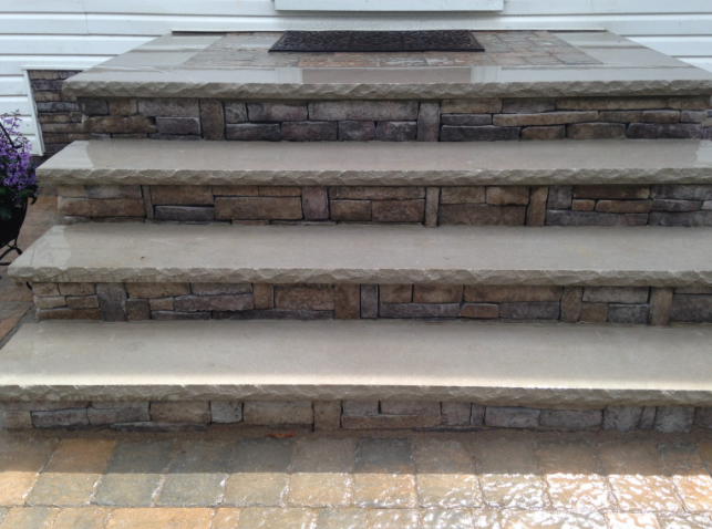 Stone steps leading up to a white door, with a matching stone facade, and a welcome mat.