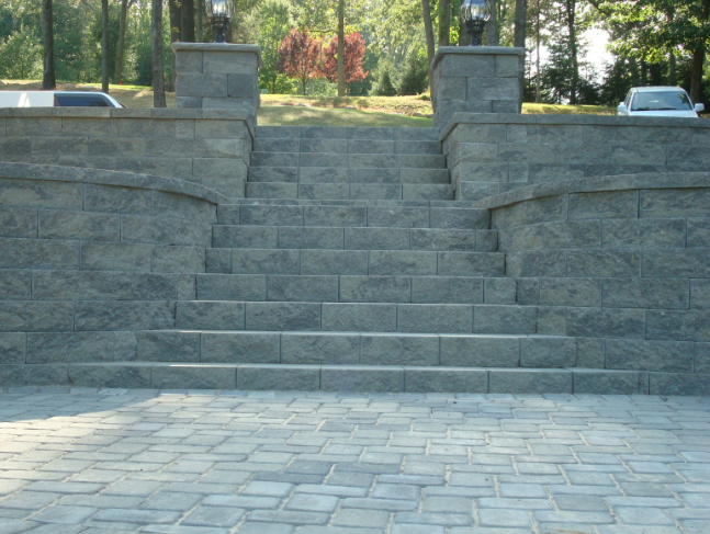 Stone staircase leading up a hill with retaining walls and a paved foreground.