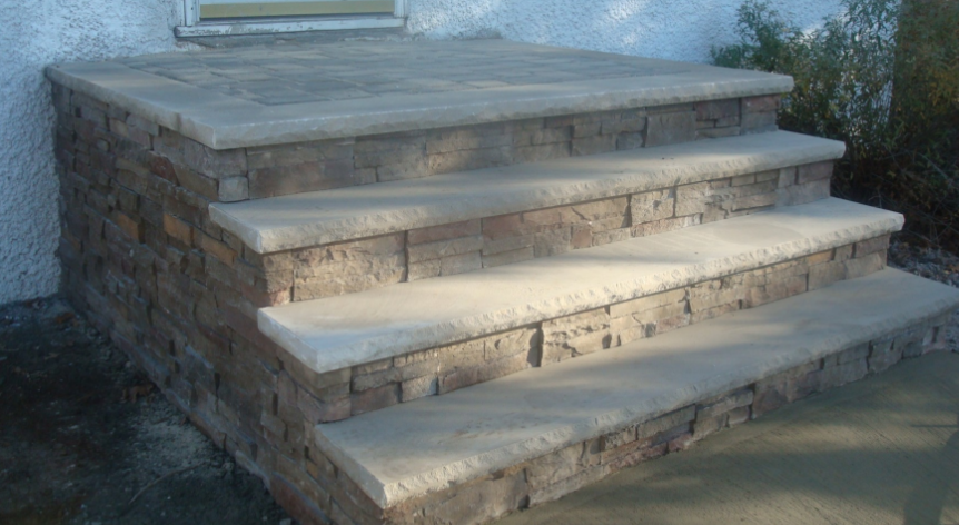 Stone steps leading up to a doorway; beige and brown stonework; sunny outdoor setting.