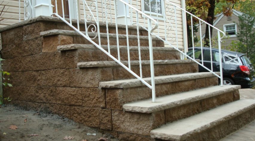 Stone steps leading up to a house with a white railing.