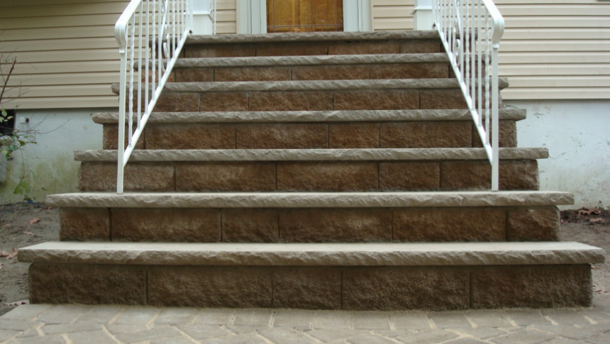 Stone steps leading up to a house entrance, with white handrails.