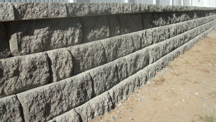Gray retaining wall built with textured blocks.